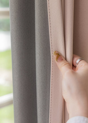 a woman's hand holding a curtain with a ring on it