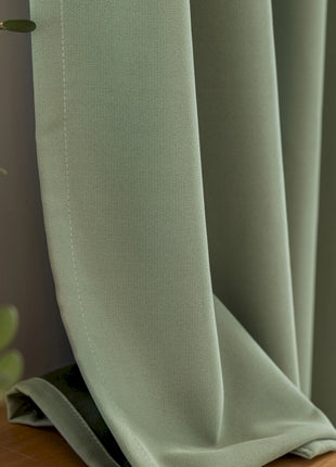 a close up of a curtain with a plant in the background
