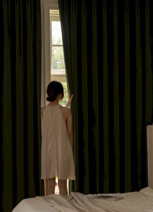 a woman standing in front of a window in a bedroom
