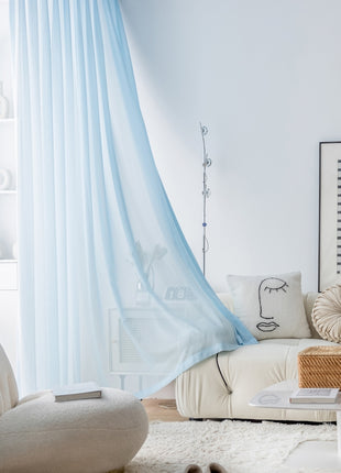 a living room with a white couch and blue drapes