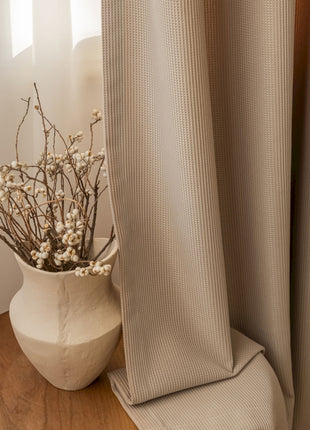 a vase of flowers sitting on a table next to a curtain