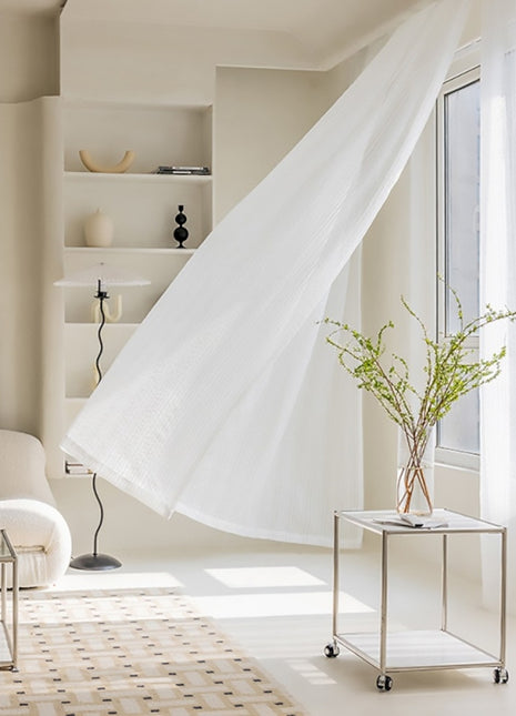 a living room with a white couch and white curtains