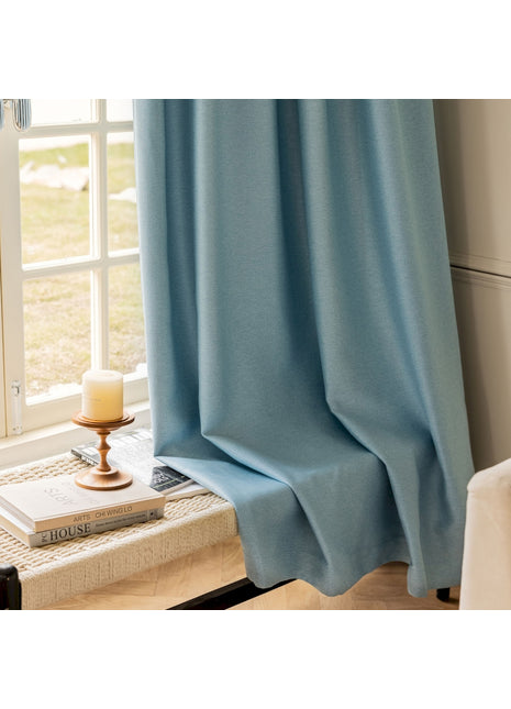 a window with a blue curtain and a candle