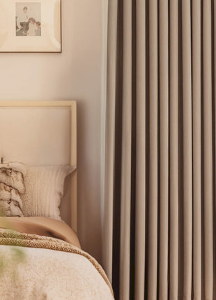 a bed sitting next to a window covered in curtains