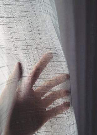 a person's hand is seen through a sheer curtain
