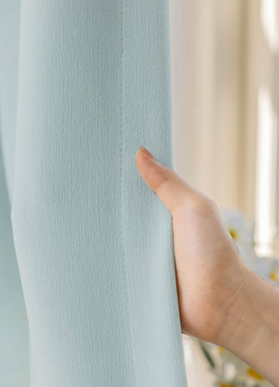 a person's hand is holding the curtain in front of a window