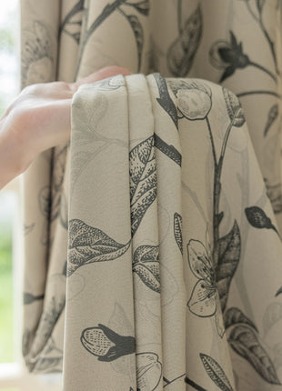 a person's hand holding a curtain with a flower pattern