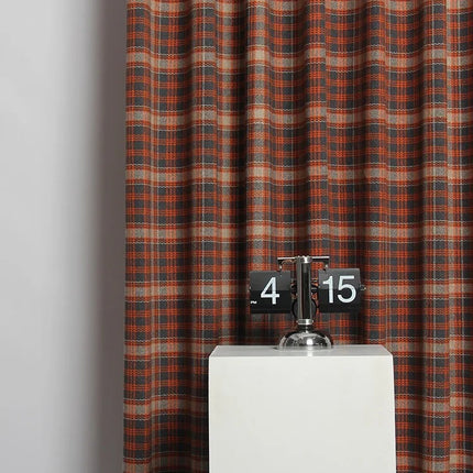 a clock on a pedestal in front of a curtain