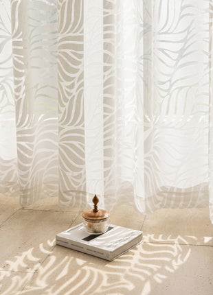 a table with a bowl on top of it in front of a curtain