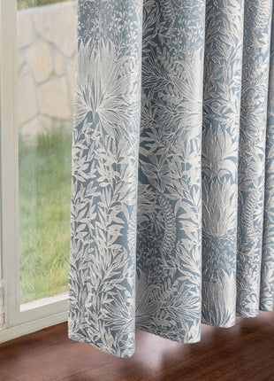 a window with a blue and white curtain hanging from it's side