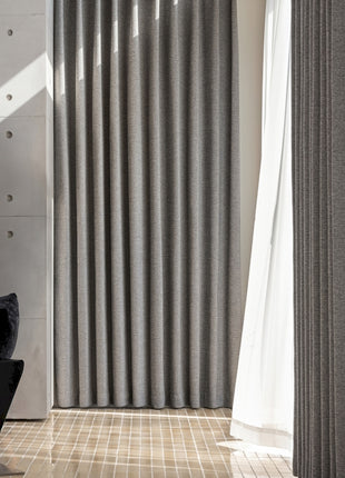 a living room with a black chair and a white curtain