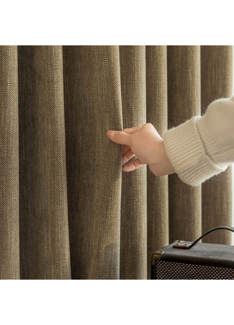 a person holding onto a curtain in front of a suitcase