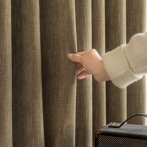 a person holding onto a curtain in front of a suitcase