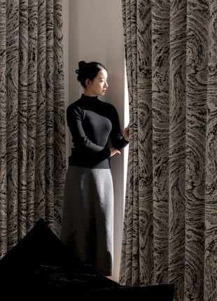 a woman standing in front of a curtain