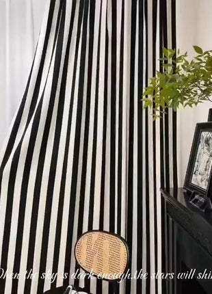 a woman standing in front of a black and white striped curtain