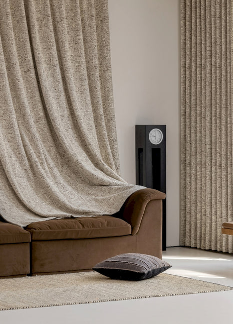 a living room with a brown couch and a tan curtain