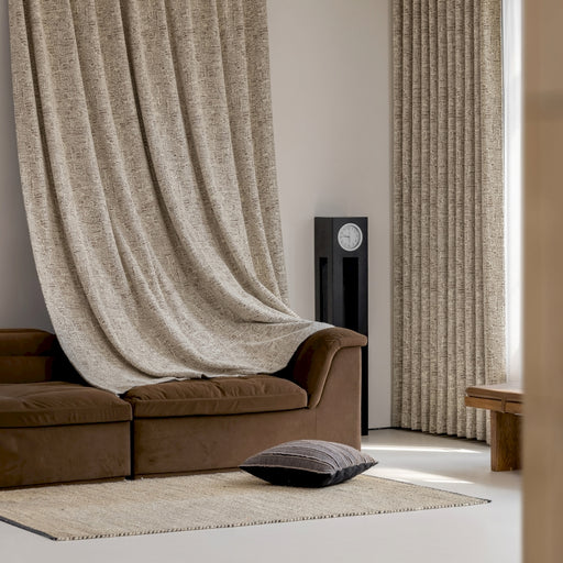 a living room with a brown couch and a tan curtain
