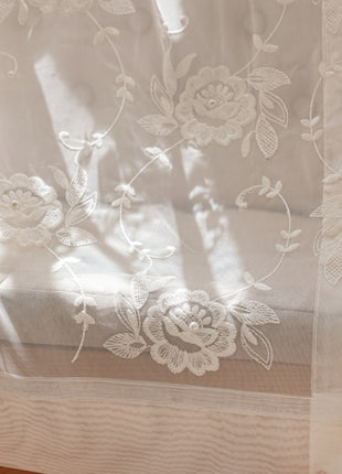 a close up of a sheer curtain with flowers on it