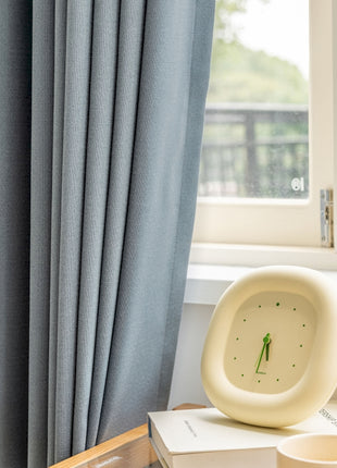 a clock sitting on top of a box next to a window