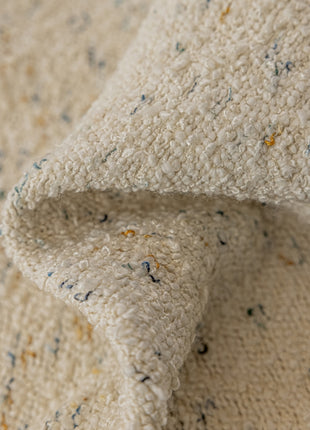 a close up of a white blanket with blue and yellow speckles
