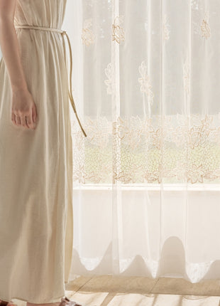 a woman in a dress standing in front of a window