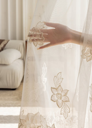 a woman's hand on a sheer curtain in a living room