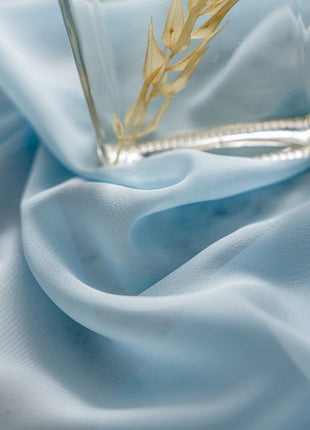 a glass vase with a plant in it on a blue cloth