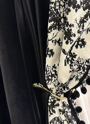 a close up of a black and white curtain with pom poms