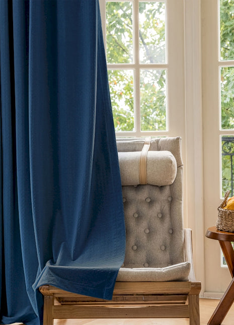 a chair sitting in front of a window with a blue curtain