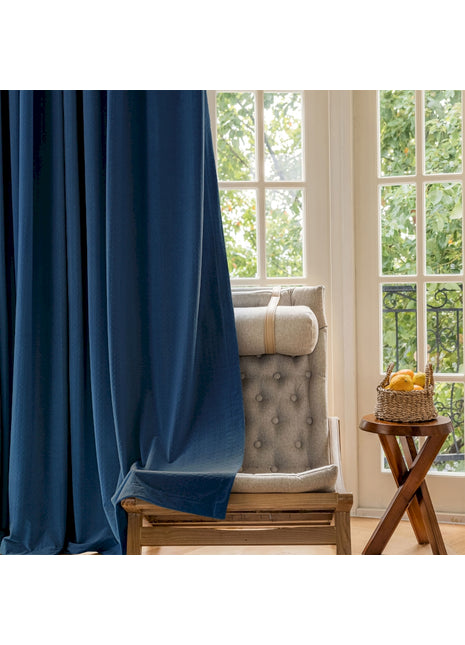 a chair sitting in front of a window with a blue curtain