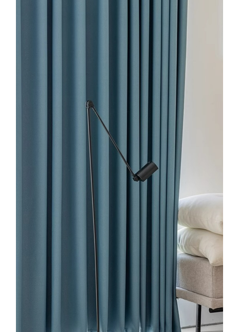 a modern living room with a blue curtain and a black floor lamp with a curved arm.