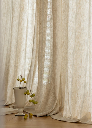 a vase with a plant in it sitting in front of a curtain