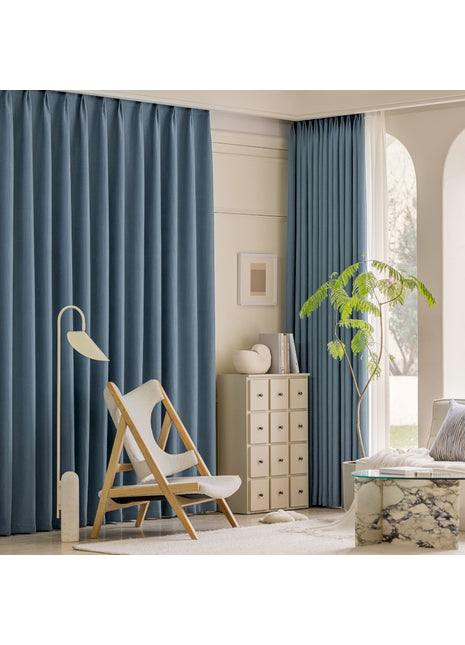 a living room with blue curtains and a white chair