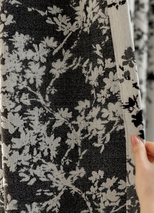 a person is holding up a black and white curtain