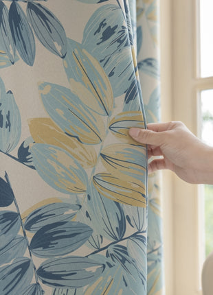 a person holding a curtain with a flower pattern