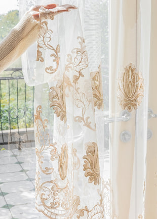 a woman is opening curtains to look out the window