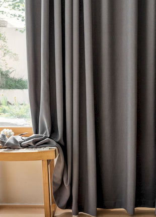 a wooden table sitting next to a window covered in curtains