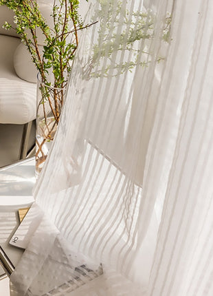 a white chair sitting next to a white curtain