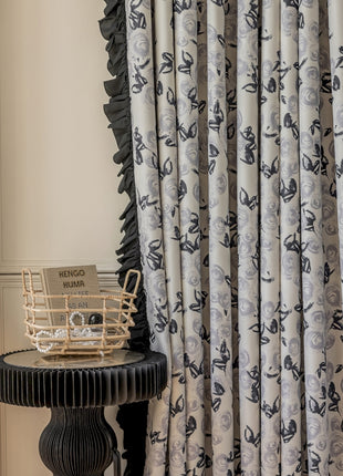 a table with a basket on top of it next to a curtain