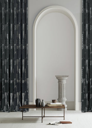 a living room with a table and two black curtains