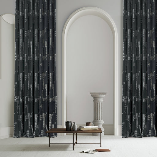 a living room with a table and two black curtains