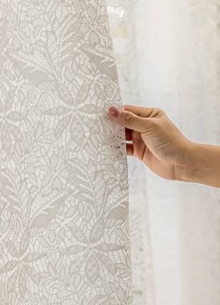 a person is holding a piece of lace on a curtain