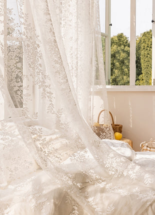 a bedroom with a white bed and white curtains