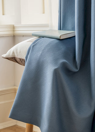 a bed with a blue blanket and a book on top of it