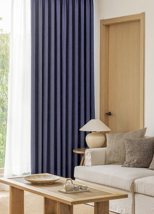 a living room filled with furniture and a window covered in blue curtains