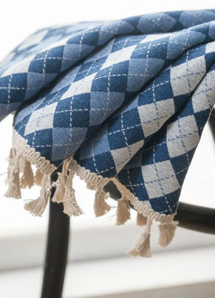 Détail du damier bleu et écru et des pompons d'un rideau bicolore