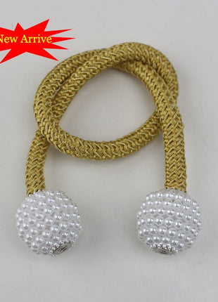 attache perles dorées et blanches sur une corde, utilisée pour des rideaux décoratifs avec attache magnétique.