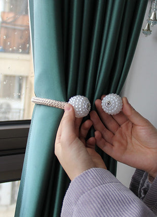 Une personne tenant une paire de perles sur un rideau, mettant en valeur l'attache rideau aimanté.